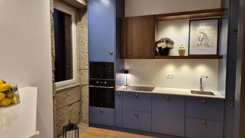 a kitchen with blue cabinets and a sink at Casas São Tiago - Arouca, conforto e natureza in Arouca