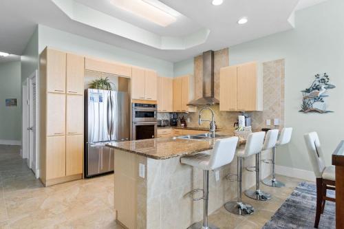 a kitchen with a refrigerator and a counter with stools at Caribe C104 in Orange Beach