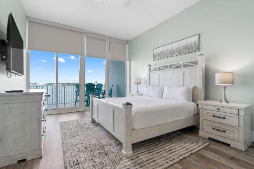 a white bedroom with a bed and a balcony at Caribe C104 in Orange Beach