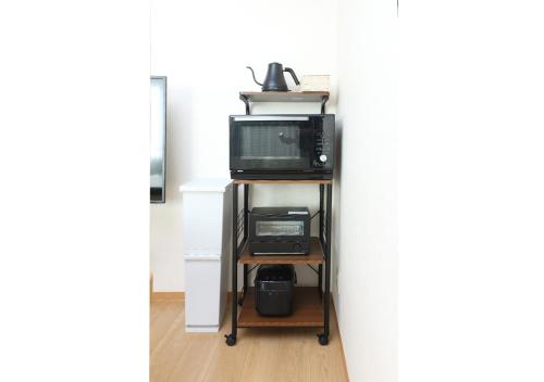 a room with a microwave and a television on a shelf at GLOCE 横須賀 HOTEL S l Yokosuka HOTEL S in Kusugaurachō
