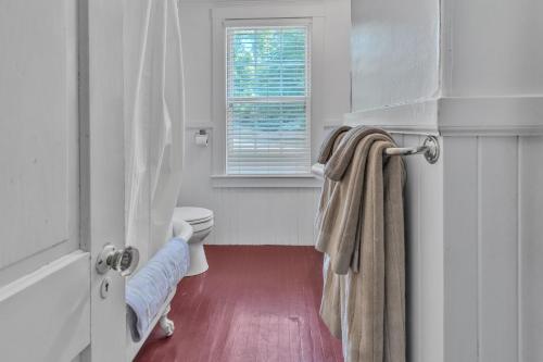 a white bathroom with a toilet and a window at Rustic Farmhouse home in Southwest Harbor