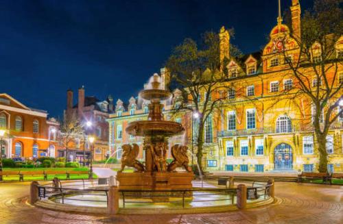 a fountain in front of a large building at night at Wigston Homestay in Wigston Magna