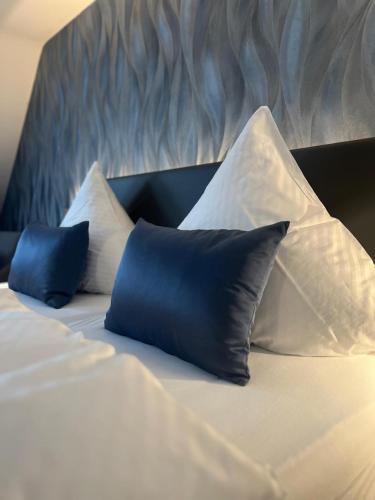 a bed with blue and white pillows on it at Hotel Restaurant Wolfsschlucht GmbH in Bad Münstereifel