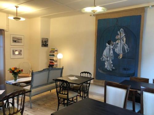 une salle à manger avec des tables et des chaises ainsi qu'une peinture murale. dans l'établissement La Modestine, à Le Monastier sur Gazeille