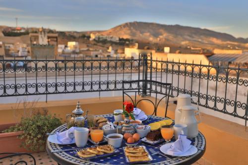 a table with breakfast food and orange juice on a balcony at Riad Louna Fes & Spa in Fès