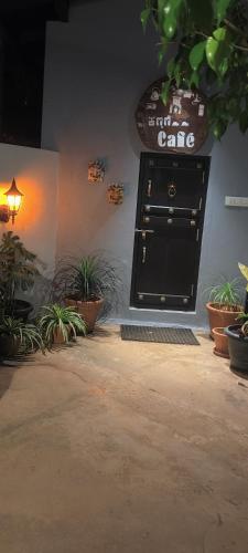 a black door with a sign on a wall with plants at Halli Hithalu Homestay in Chikmagalūr