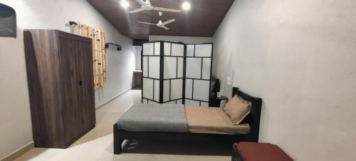 a small bedroom with a bed and a ceiling fan at Halli Hithalu Homestay in Chikmagalūr