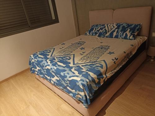 a bed with a blue and white comforter on it at Appartement de vacances in Agadir