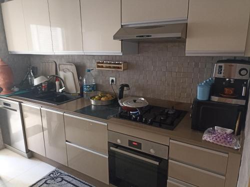 a kitchen with a stove top oven next to a sink at Appartement de vacances in Agadir