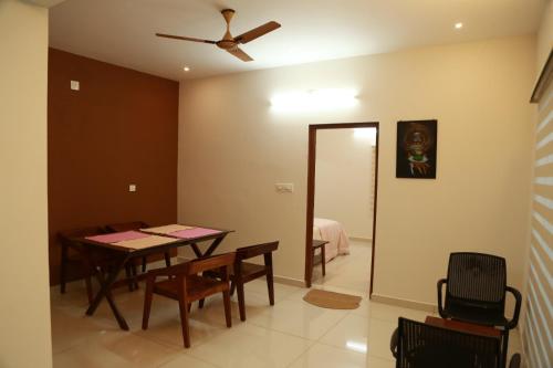 a dining room with a table and a ceiling fan at Lush Green-Homestay in Pooppara