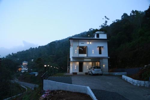 a house on a hill with a car parked in the driveway at Lush Green-Homestay in Pooppara