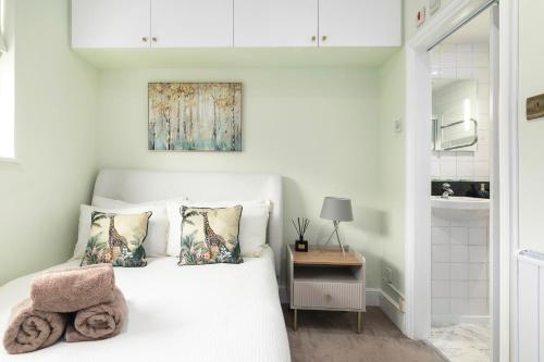 Un dormitorio con una cama blanca con dos almohadas. en Cosy flat 5 min from Holland Park station! London, en Londres