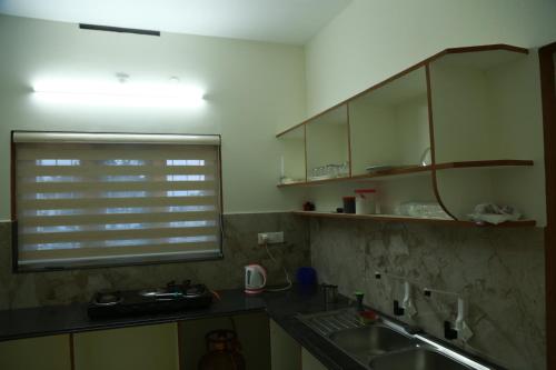 a kitchen with a sink and a window at Lush Green-Homestay in Pooppara
