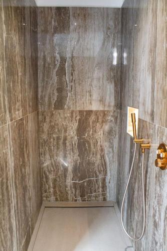 La salle de bains est pourvue d'une douche et d'un mur en pierre. dans l'établissement Villa Lesia, à Sainte-Lucie de Porto-Vecchio