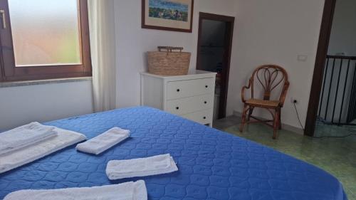 a bedroom with a blue bed with towels on it at Casa blu Arbatax con giardino e terrazza in Tortolì
