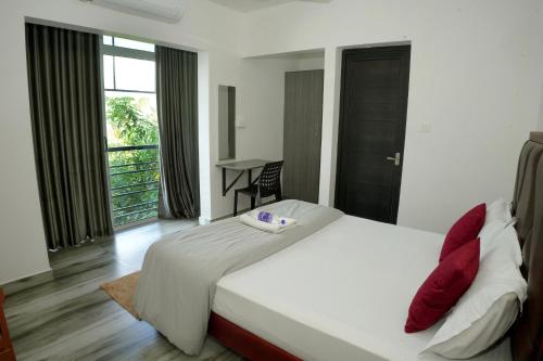 a bedroom with a large white bed with red pillows at Dune Homestay in Alleppey
