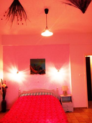 a pink bedroom with a bed with a red blanket at skiathosrooms-appartments for holidays in Skiathos Town