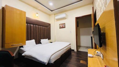 a hotel room with a bed and a tv at Hotel New Holiday in Bhilwara
