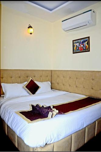 a bedroom with a large bed with white sheets at Hotel New Holiday in Bhilwara