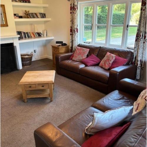 a living room with a leather couch and a coffee table at The Old Cricket pavilion, Bodiam, East Sussex in Bodiam
