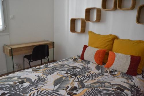 Cette chambre comprend un lit avec des oreillers colorés et un bureau. dans l'établissement Palavas les Flots Appartement T2 à 5 min de la plage, à Palavas-les-Flots