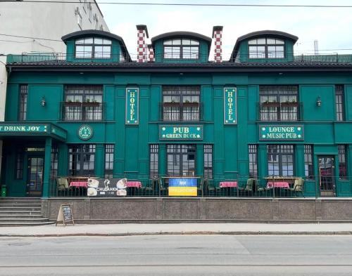 a green building with tables and chairs in front of it at Green Duck Hotel in Kharkiv