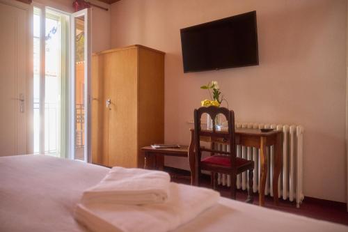 a bedroom with a desk and a chair and a television at Hôtel Restaurant Le Botaniste in Prats-de-Mollo-la-Preste