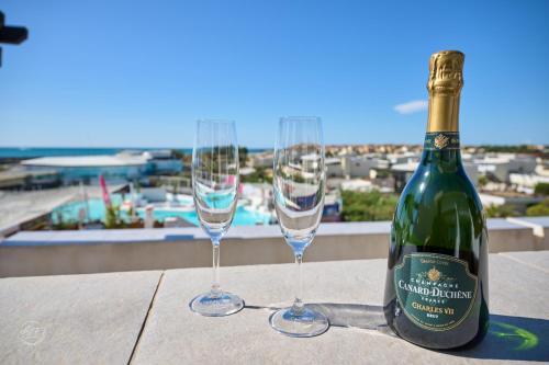 une bouteille de vin et deux verres sur une table dans l'établissement COURSIVES RED-LIGHT 108 Vue Mer, au Cap d'Agde