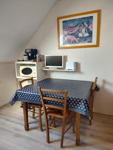 Una mesa con sillas y un escritorio con una computadora. en Studio au 2e étage de notre maison de ville, en Caen