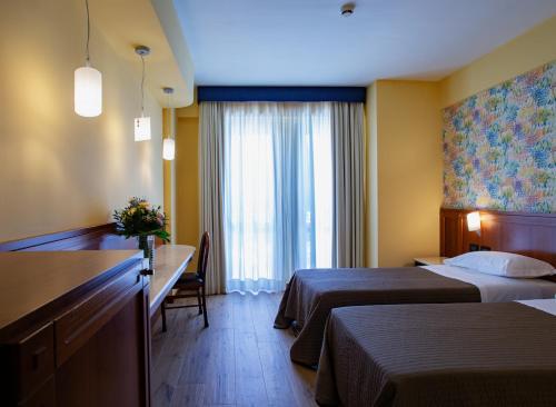 a hotel room with two beds and a desk at Hotel Miralago in Piediluco