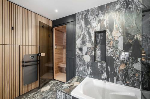 a bathroom with a bath tub and a stone wall at App d'exception 8pers, 66 m2, plein sud, confort, sauna, au calme, rénovation 2024 in Val Thorens