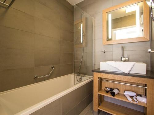 une salle de bain avec un lavabo, une baignoire et un miroir dans l'établissement Appartement cosy 3 chambres avec piscine, spa et parking - Arcs 1800 - FR-1-352-32, à Arc 1800