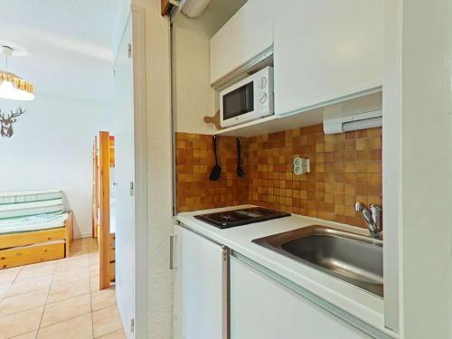 une petite cuisine avec un évier et un micro-ondes dans l'établissement Studio skis aux pieds avec parking - Montgenèvre, 650m du centre et ESF - FR-1-330D-1, à Montgenèvre