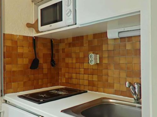 une cuisine avec un évier et un micro-ondes dans l'établissement Studio skis aux pieds avec parking - Montgenèvre, 650m du centre et ESF - FR-1-330D-1, à Montgenèvre