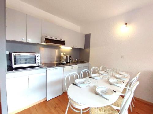 une cuisine avec une table avec des chaises et un micro-ondes dans l'établissement Appartement cosy 6 pers, Piau-Engaly, balcon et casier à ski - FR-1-457-204, à Aragnouet
