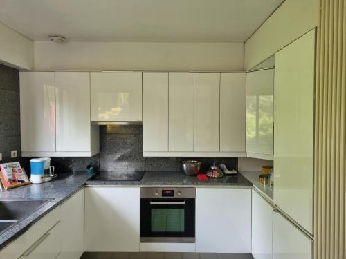 une cuisine avec des armoires blanches et une cuisinière dans l'établissement Belle Maison d'Art Verdoyante & jardin, à Saint-Rémy-lès-Chevreuse