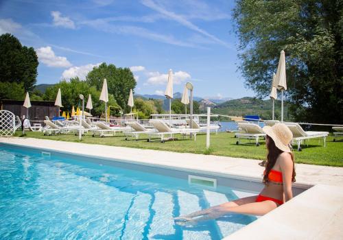 a woman in a hat sitting next to a swimming pool at Hotel Miralago in Piediluco