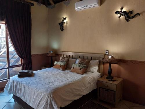 a bedroom with a bed and two lamps and a window at Assegai Lodge in Moheme