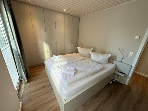 a small bedroom with a bed with white sheets and pillows at Wasserhaus Schlei in Schleswig