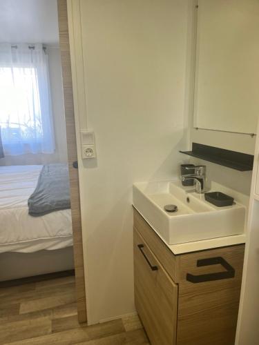 une petite salle de bain avec un lavabo et un lit dans l'établissement Mobil Home CasaLuca 3 chambres 2 Salles d'eau, à Canet