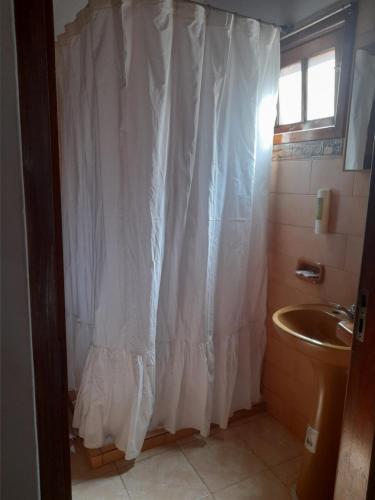 a bathroom with a white shower curtain and a sink at Iguazú Cataratas Dpto2 in Puerto Iguazú
