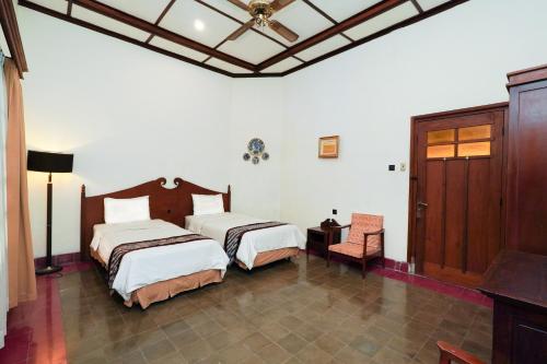 a bedroom with two beds and a table and a chair at Indraloka Heritage Homestay in Yogyakarta