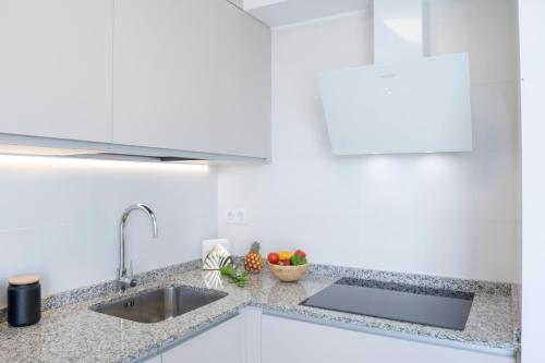a kitchen with white cabinets and a sink at Casa Hortencia - Beautiful seaside apartment - Puerto de Las Nieves in Agaete