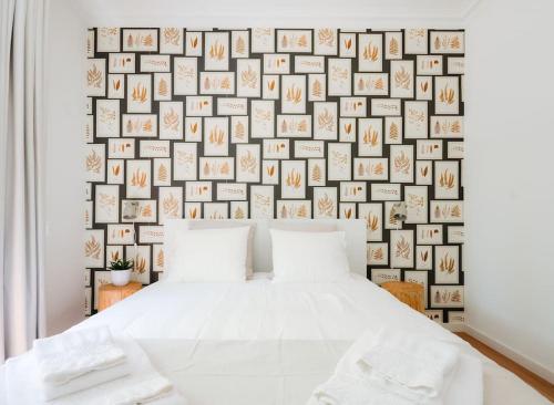 a bedroom with a white bed and a wall of pictures at Cascais Center Family Apartment with Courtyard in Cascais