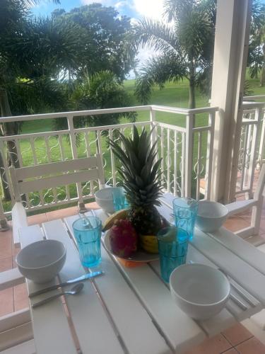 a table with a pineapple and blue glasses on a porch at la Désirade in Sainte-Luce