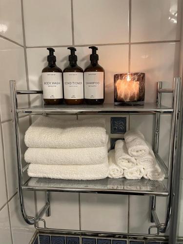 a shelf with three bottles of soap and towels at Ryenstubben in Oslo