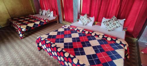 two beds in a room with red curtains at New snow view resort pahalgam in Pahalgām