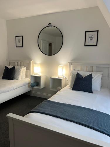 a bedroom with two beds and a mirror on the wall at The Nook - Town Centre Apartment in Hoddesdon