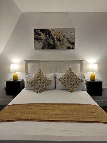 a bedroom with a white bed with two lamps at The Nook - Town Centre Apartment in Hoddesdon