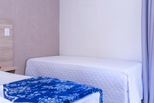 a bedroom with two beds with blue and white sheets at Pousada Piri Paim in Pirenópolis